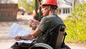 Construction workers wearing safety gear at a building site reviewing architectural plans.