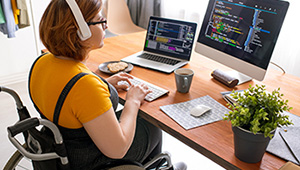 Information technology professional working at a computer with multiple monitors displaying software and data.