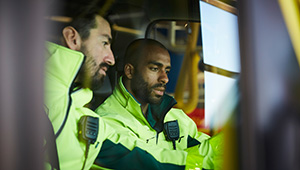 Emergency responders in uniform standing near a public safety vehicle.